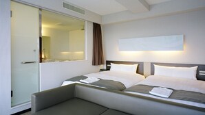 Una habitación de hotel con cama doble, mesita de noche, espejo y ventana con cortinas.