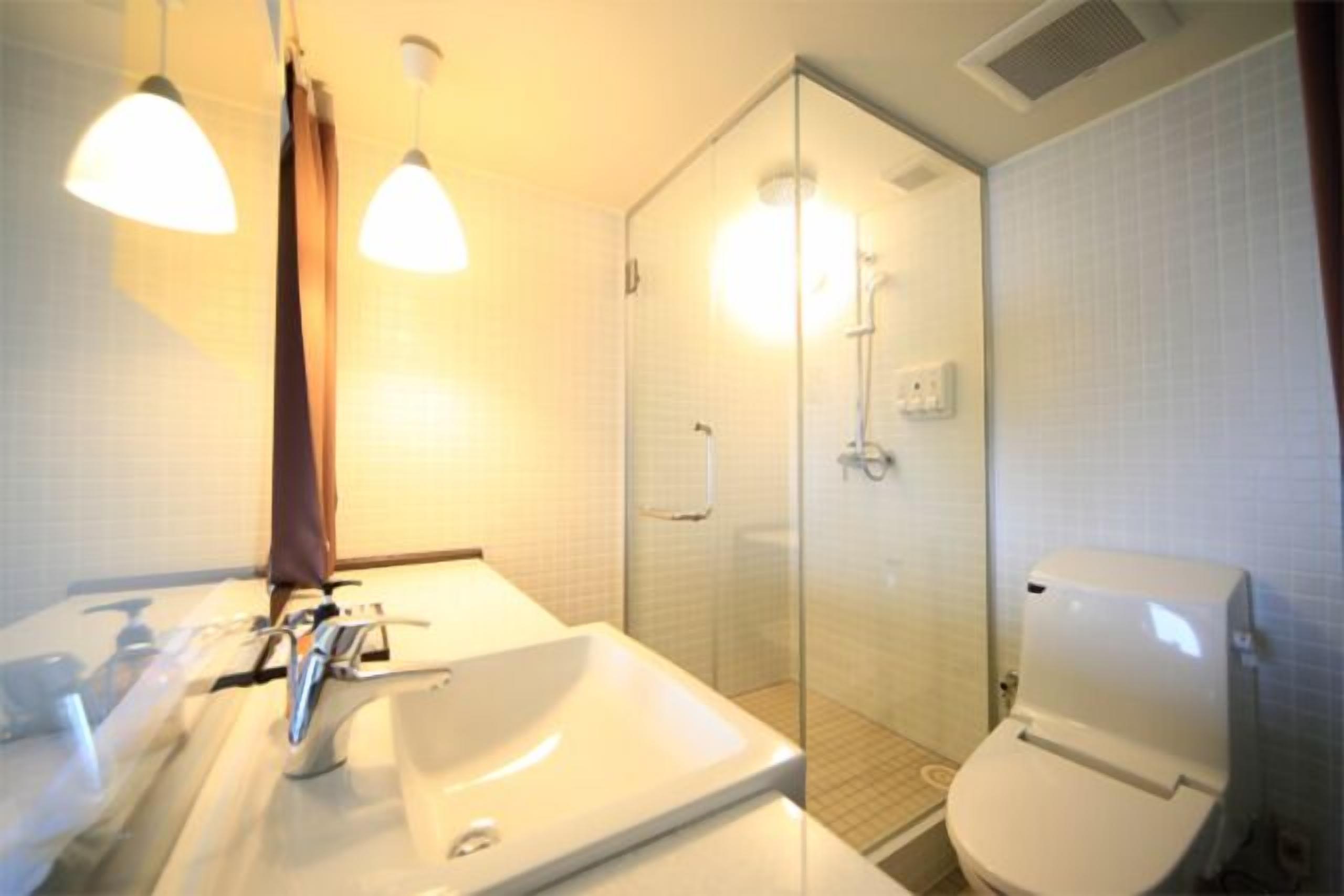 A modern bathroom with a glass-enclosed shower, a white sink, and a toilet.