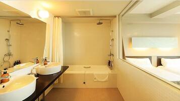 A hotel bathroom with two sinks, a bathtub, and a shower.