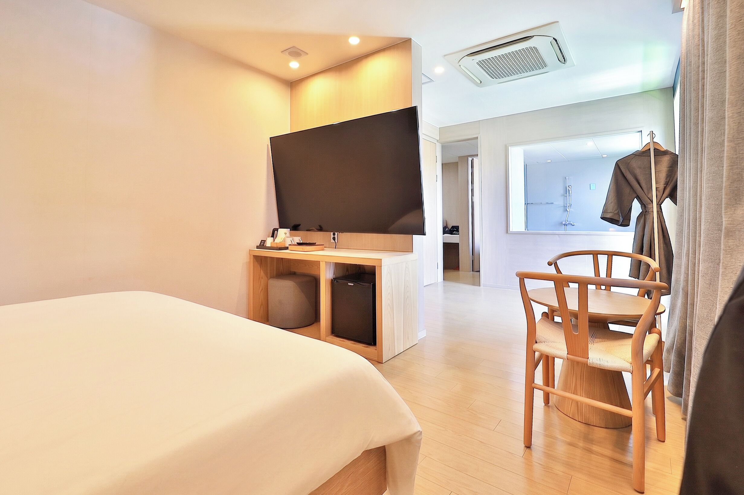 A hotel room with a bed, a desk with a chair, a wardrobe, and a large mirror.