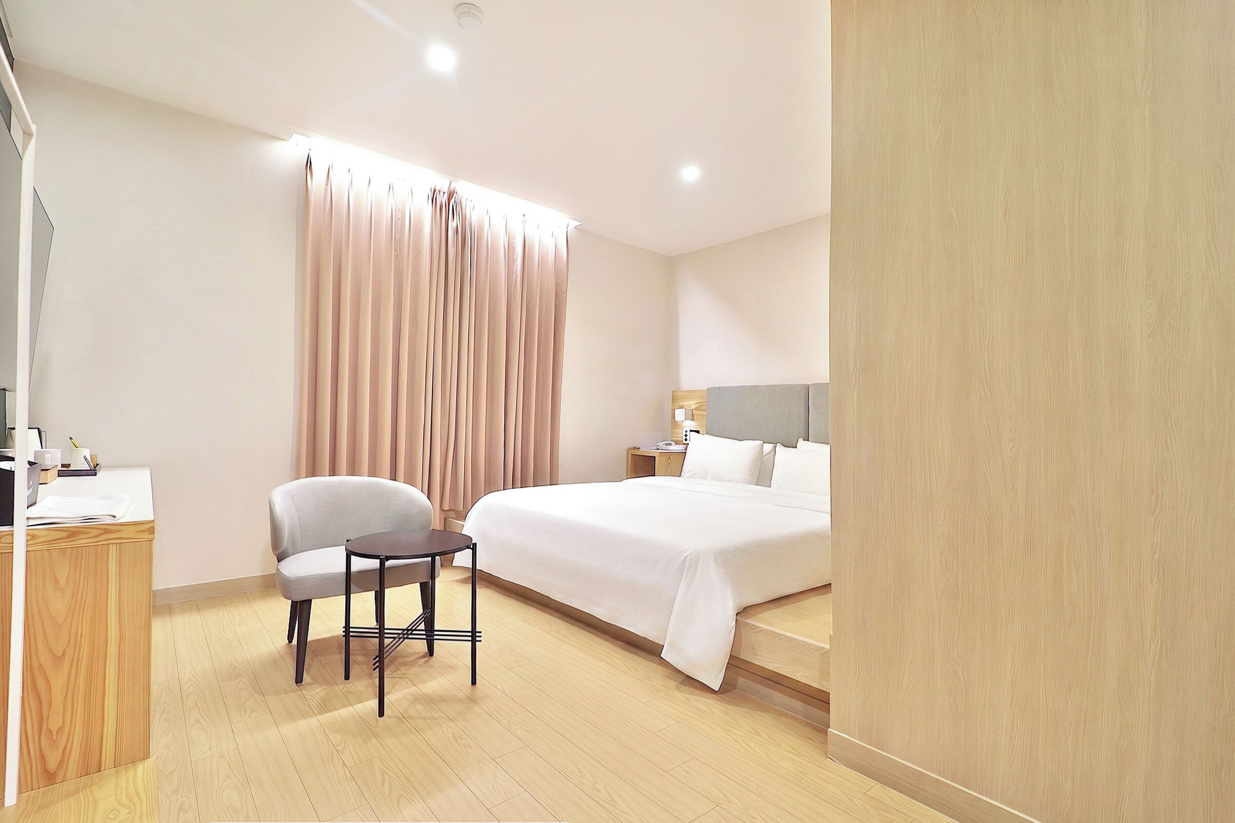 Ein Hotelzimmer mit Bett, Stuhl, Schreibtisch und Nachttisch.