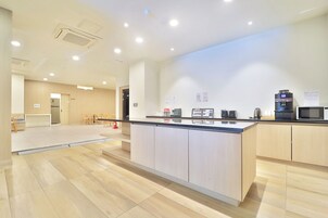 Cocina moderna con gabinetes de madera, una isla central y varios electrodomésticos, incluyendo una cafetera y un microondas.