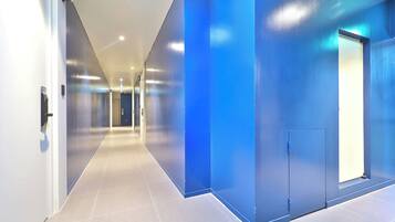 Un pasillo moderno con una pared azul decorativa, una puerta con picaporte y un accesorio de iluminación en el techo.