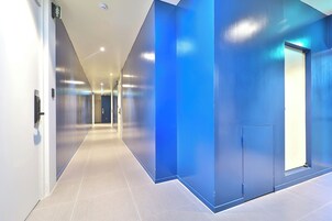Un pasillo moderno con una pared azul decorativa, una puerta con picaporte y un accesorio de iluminación en el techo.
