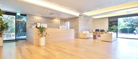 Un área de recepción moderna con mostrador, asientos y un gran ventanal que da al exterior.
