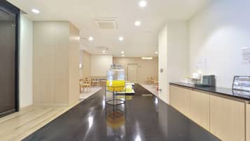 A modern kitchen area with a black countertop, stainless steel appliances, and a seating area with wooden chairs.