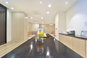Un área de cocina moderna con encimera negra, electrodomésticos de acero inoxidable y una zona de estar con sillas de madera.
