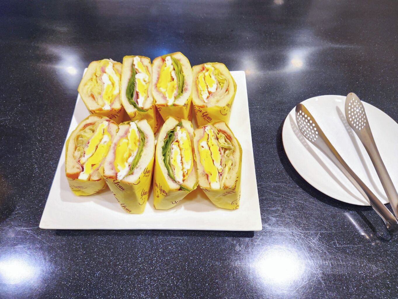 Un plato de sándwiches sobre una mesa, con dos cubiertos a un lado.
