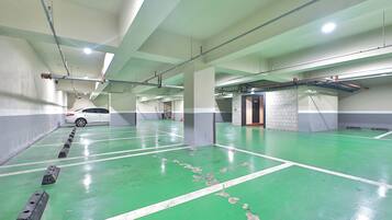 A multi-level parking garage with green flooring, white lines, and a white car parked in the distance.