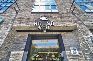 Un edificio de ladrillo con un cartel que dice 'HOUND HOTEL' y el logotipo de un perro.