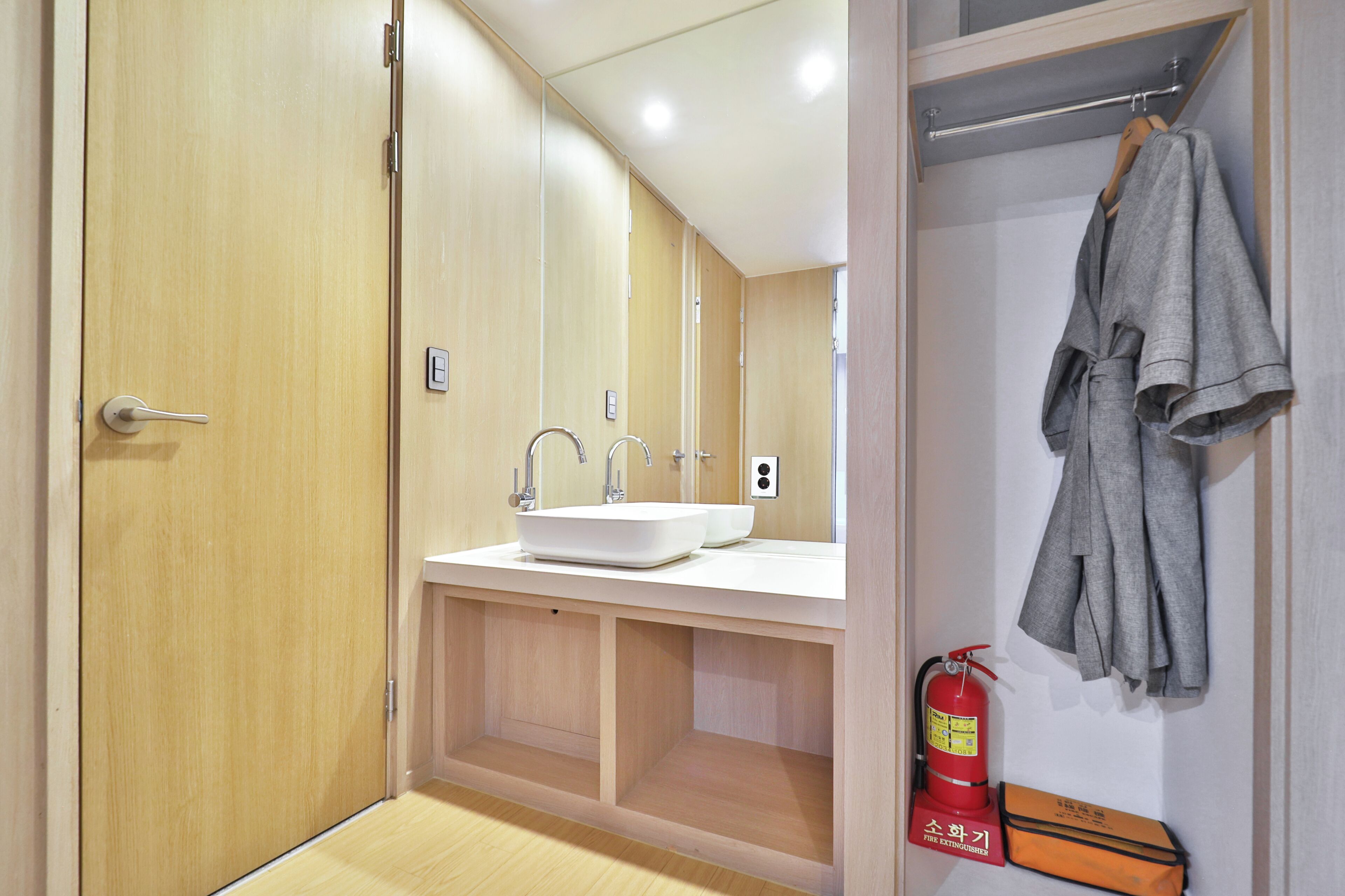 A bathroom with a wooden door, a white sink, a mirror, and a towel rack.