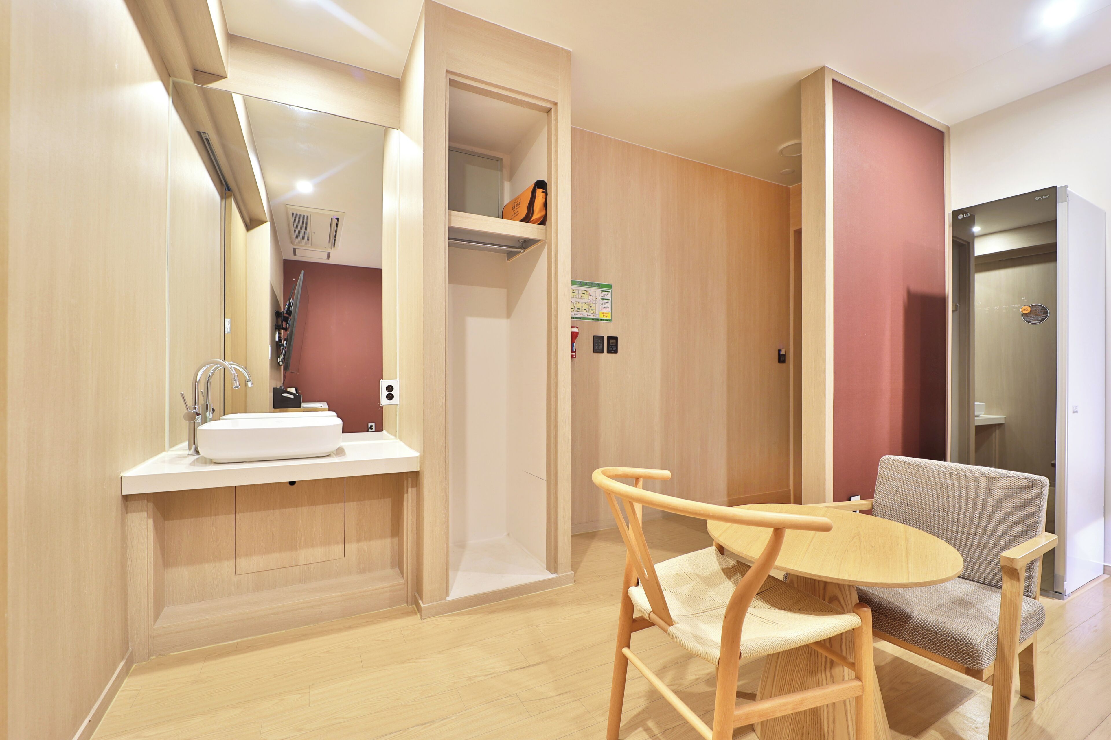 Een moderne badkamer met een wastafel, spiegel en handdoekrek. Er staat een houten stoel en een klein tafeltje met een stoel.