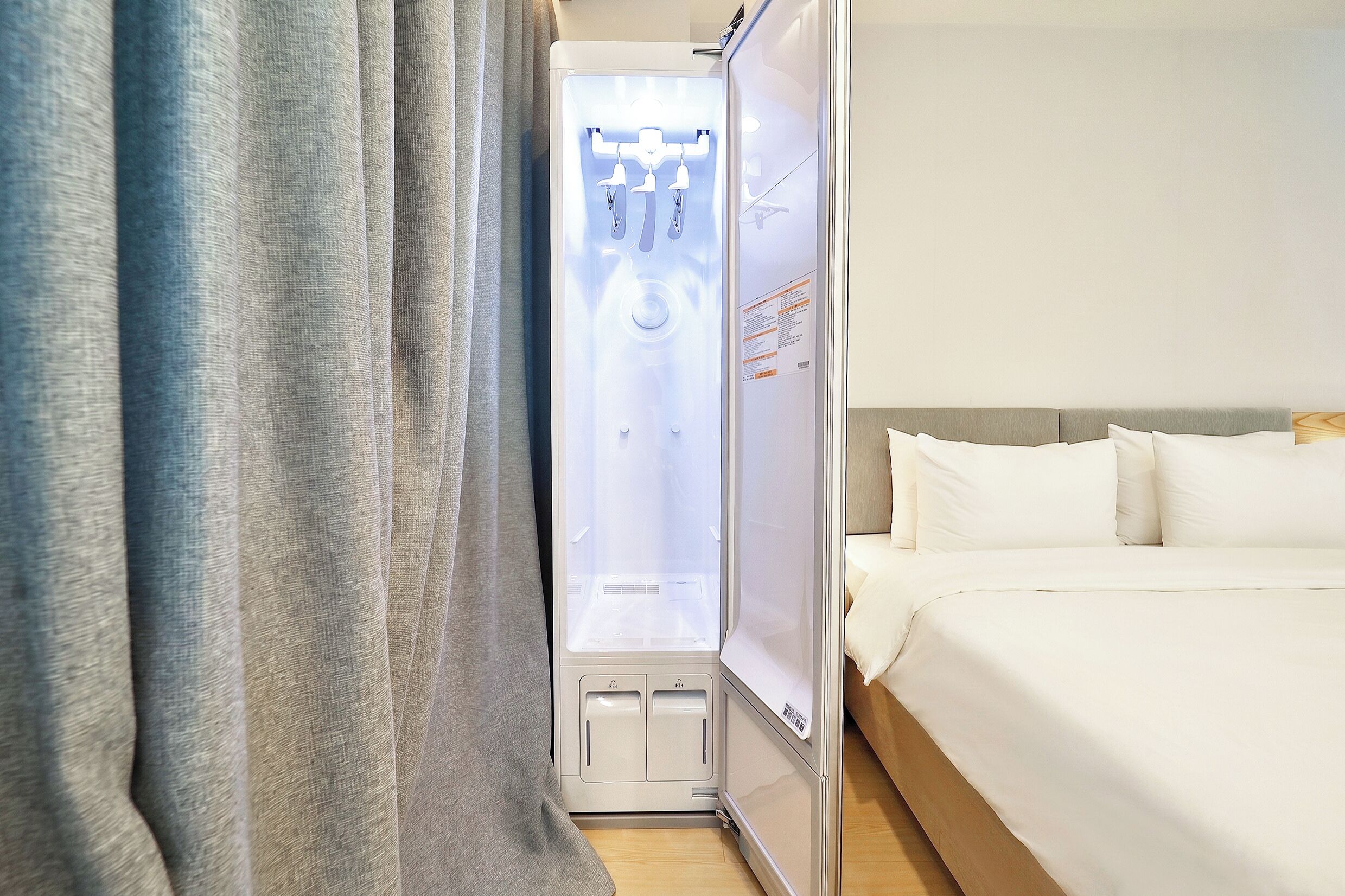 Una habitación de hotel con cama, cortinas y zona de ducha.