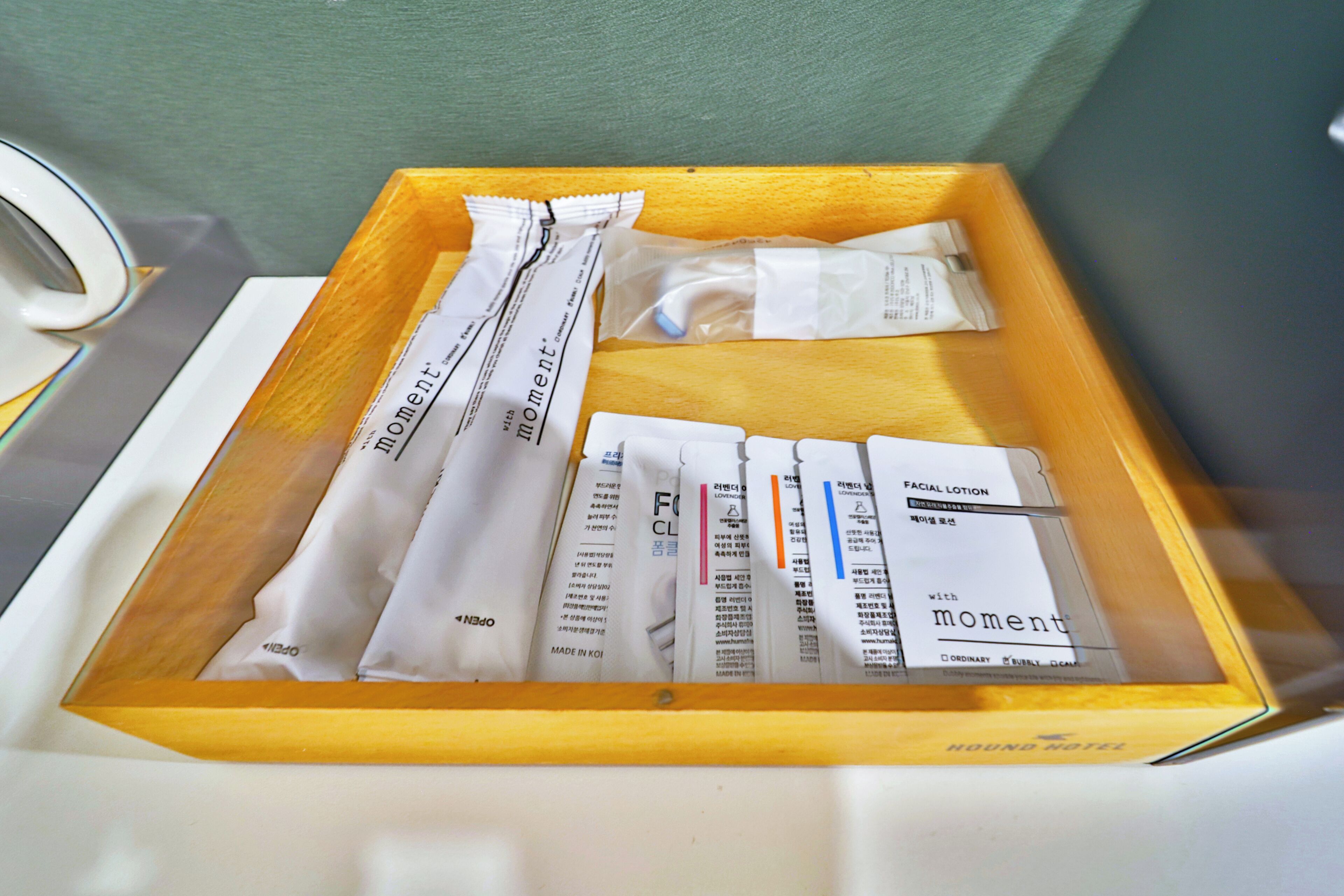 A wooden tray containing various toiletries including a facial lotion and other personal care items.