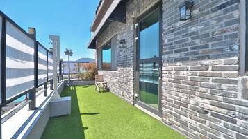 A modern building with a stone facade, large windows, and a green artificial lawn.