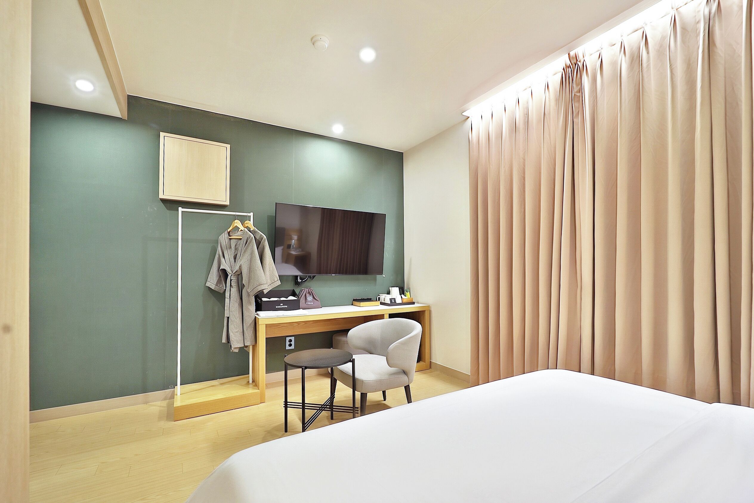 A hotel room with a bed, a desk with a chair, a television, and a wardrobe.