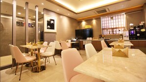 A modern dining area with a bar, multiple seating options, and a kitchen in the background. - Changwon AT Business Hotel (Changwon)