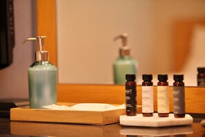 Una encimera de baño con un dispensador de jabón, una botella de champú y tres pequeñas botellas de productos para el cabello.