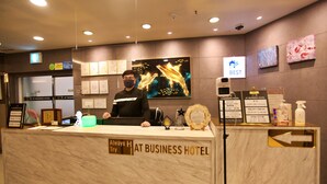 A reception desk at a business hotel with a marble top, framed certificates, and a large digital screen displaying a dolphin. - Changwon AT Business Hotel (Changwon)