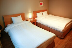 Una habitación de hotel con dos camas individuales, una mesita de noche con lámpara y un cuadro en la pared.