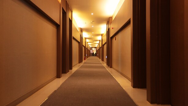 A hotel corridor with a carpeted floor, wooden doors, and a ceiling with recessed lighting. - Changwon AT Business Hotel (Changwon)