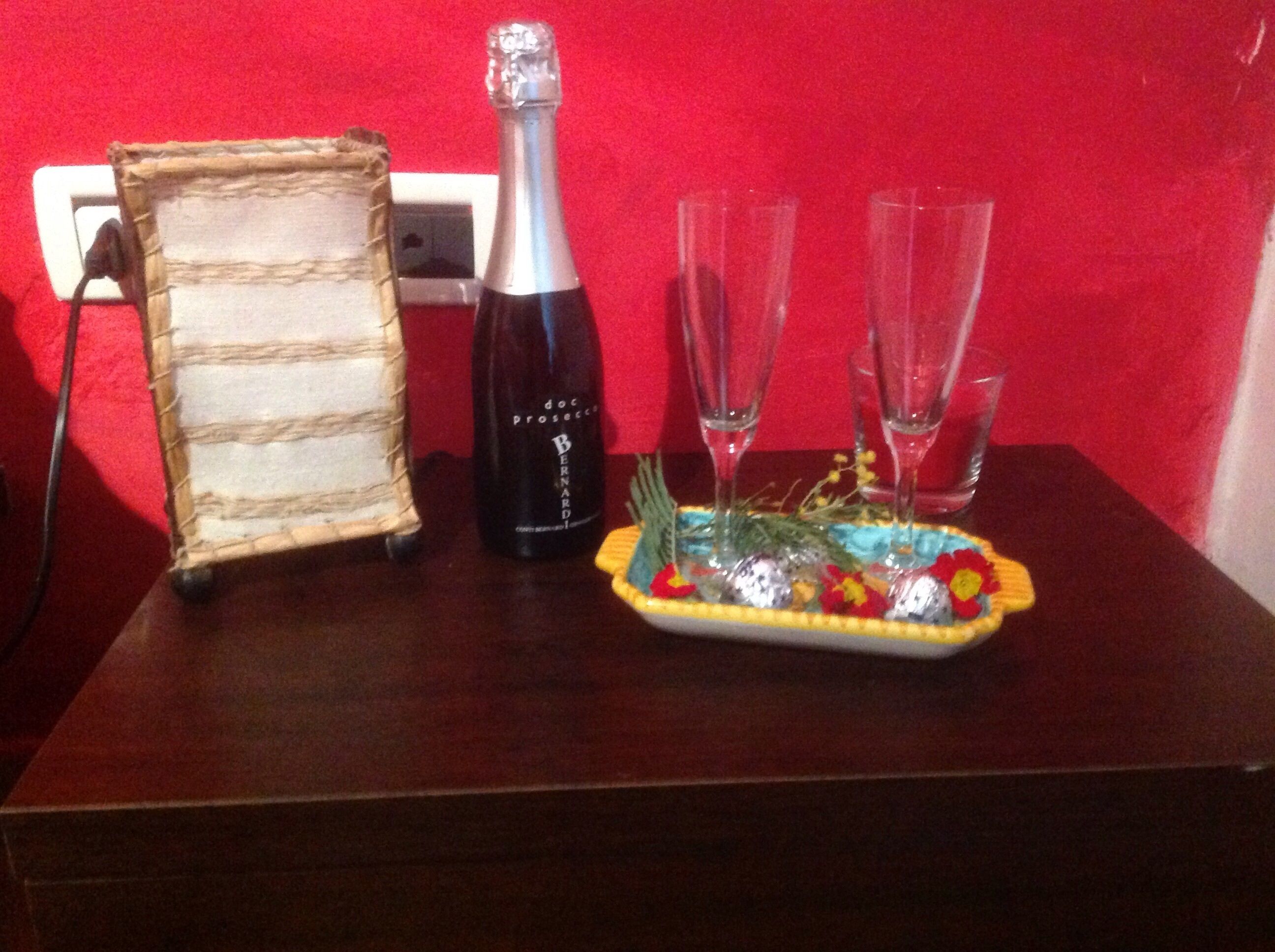 A wooden table with a bottle of wine, two glasses, and a decorative plate with flowers.