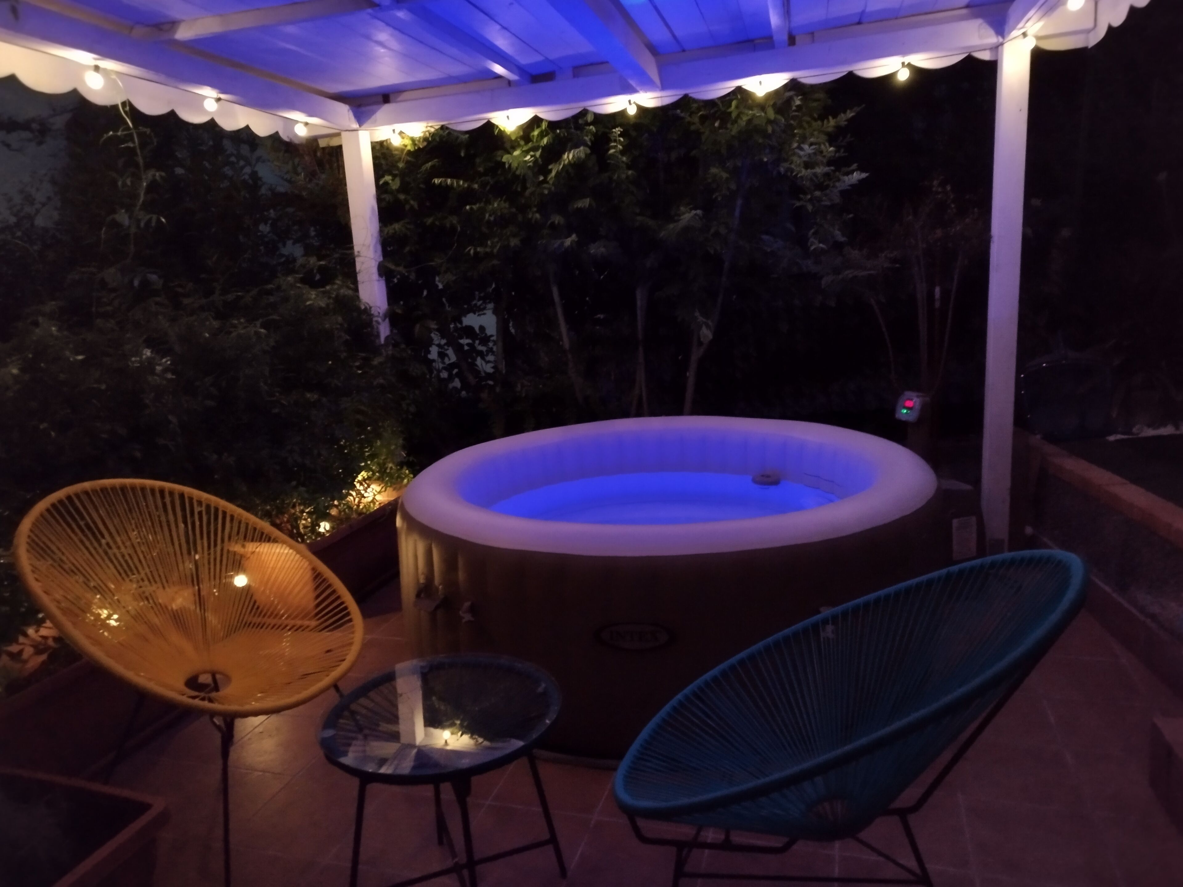 Un área de hidromasaje al aire libre con dos sillones y un toldo.