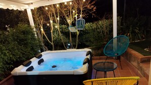 Ein Whirlpool mit digitaler Anzeige, umgeben von Sitzgelegenheiten und Lichterketten.