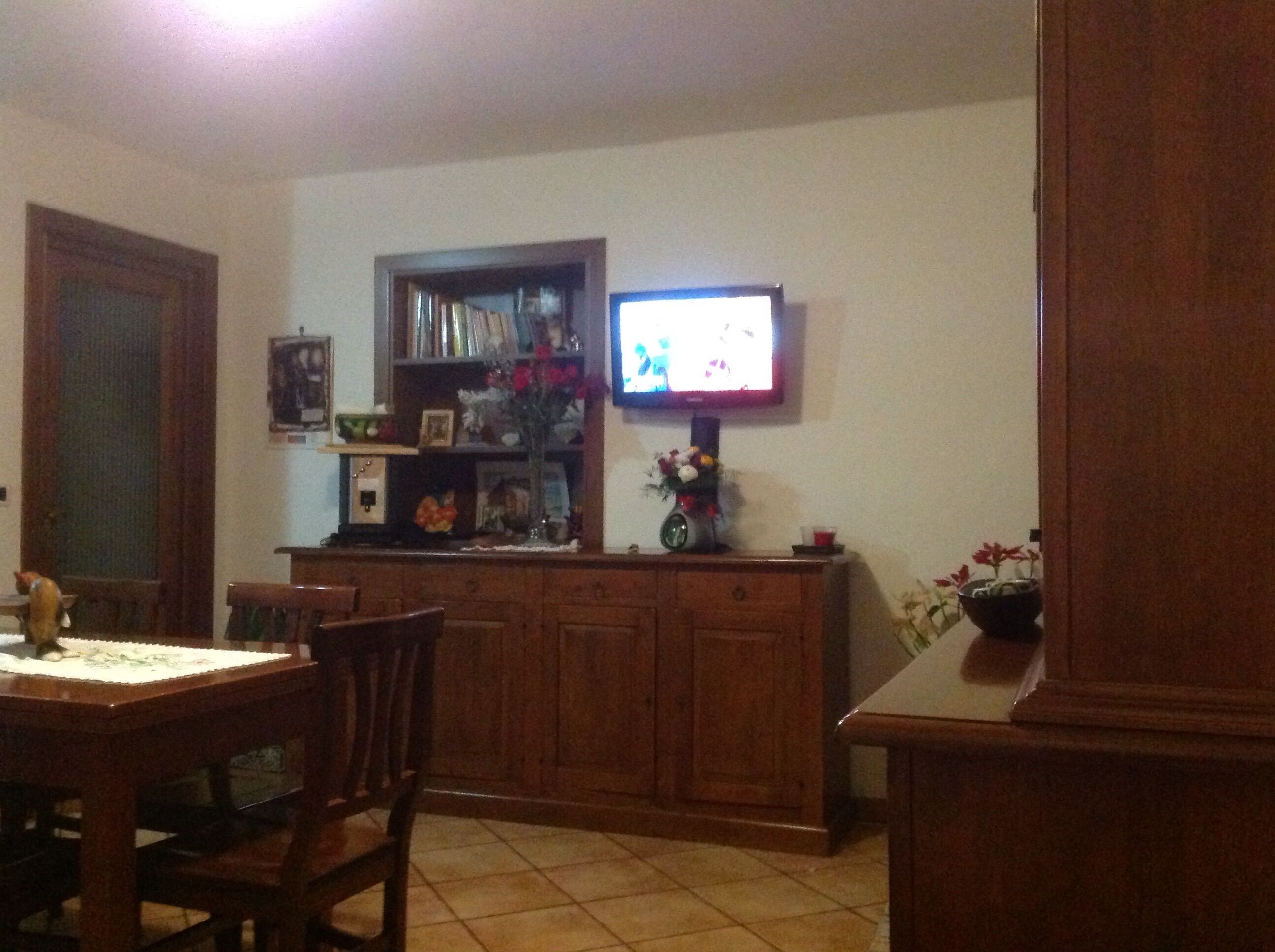 Ein Essbereich mit Holzausbau, einem an einer Ablage montierten Fernseher und einem Esstisch mit Stühlen.