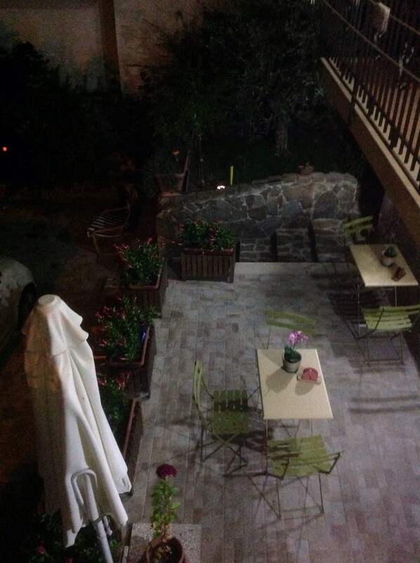 An outdoor patio area with stone flooring, green chairs, a table with a potted plant, and a stone wall. - La Vecchia Taverna B&B (Prignano Cilento)