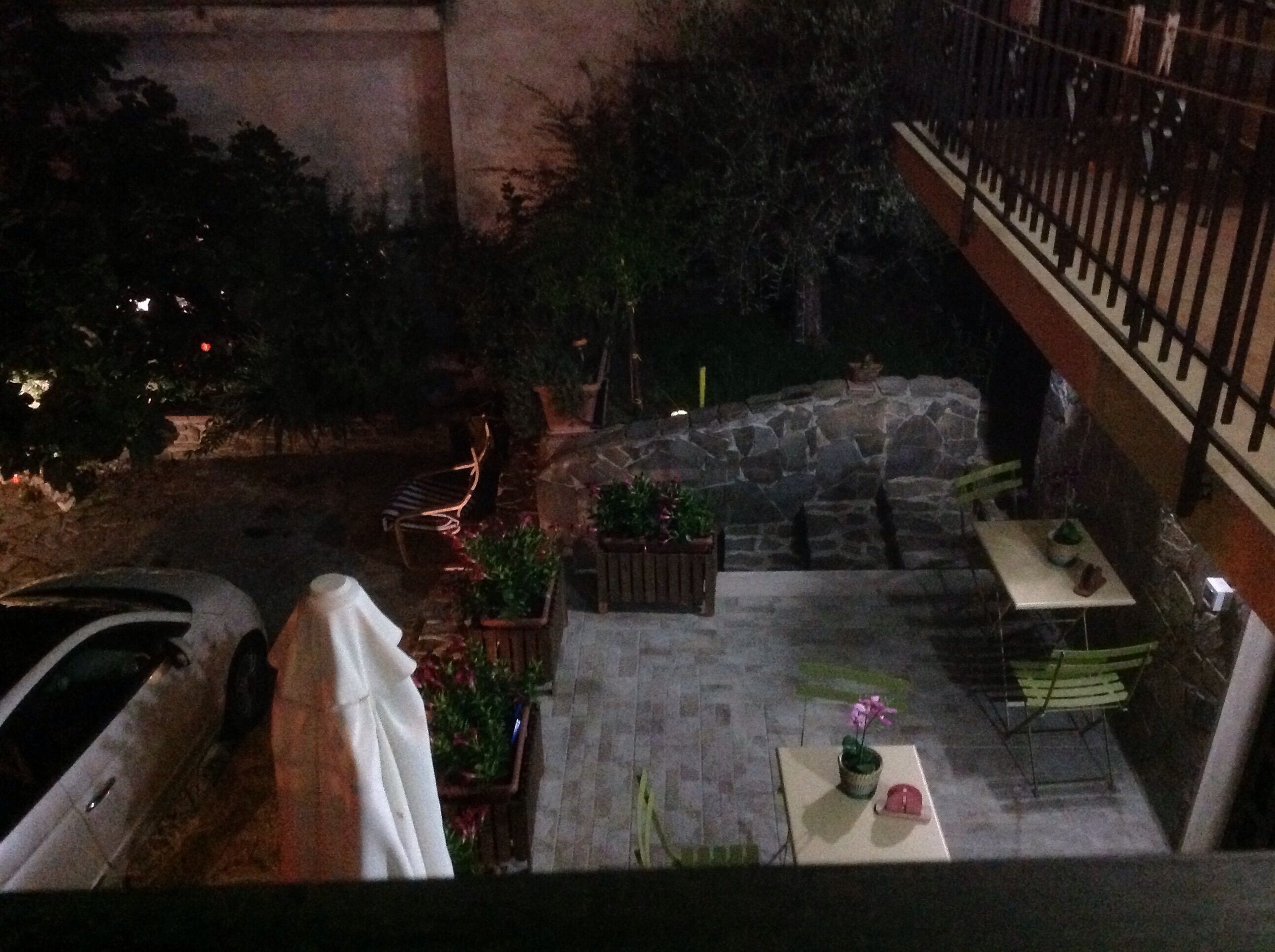 Un patio al aire libre con suelo de piedra, plantas en macetas y mobiliario exterior.