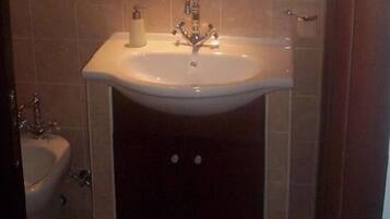 A bathroom with a white sink, a mirror above it, and a toilet to the left.