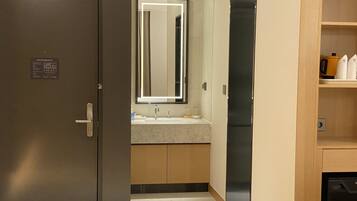 A modern bathroom with a large mirror, a sink, and a toilet.