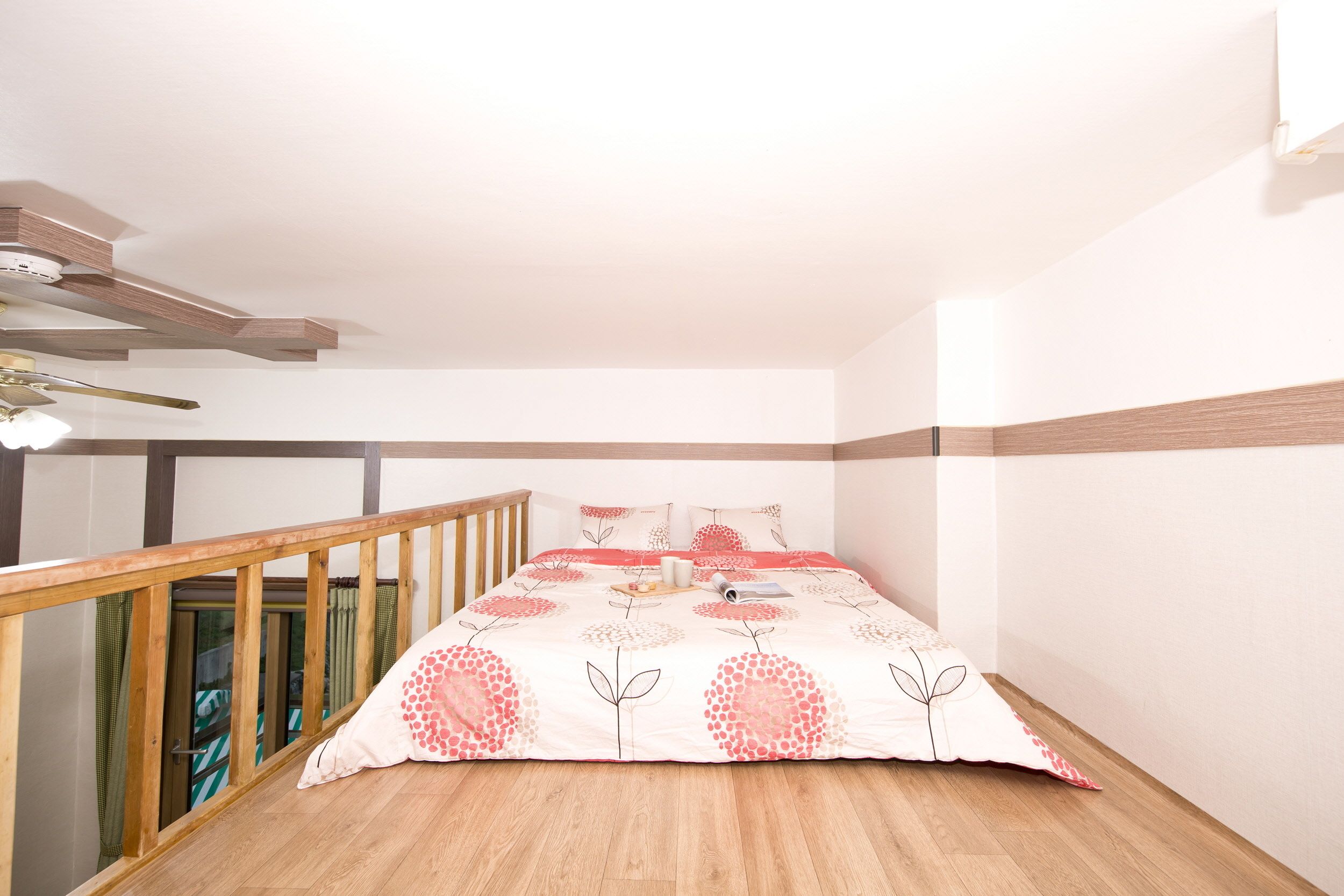 A bedroom with a wooden bed frame, a ceiling fan, and a view of the balcony.