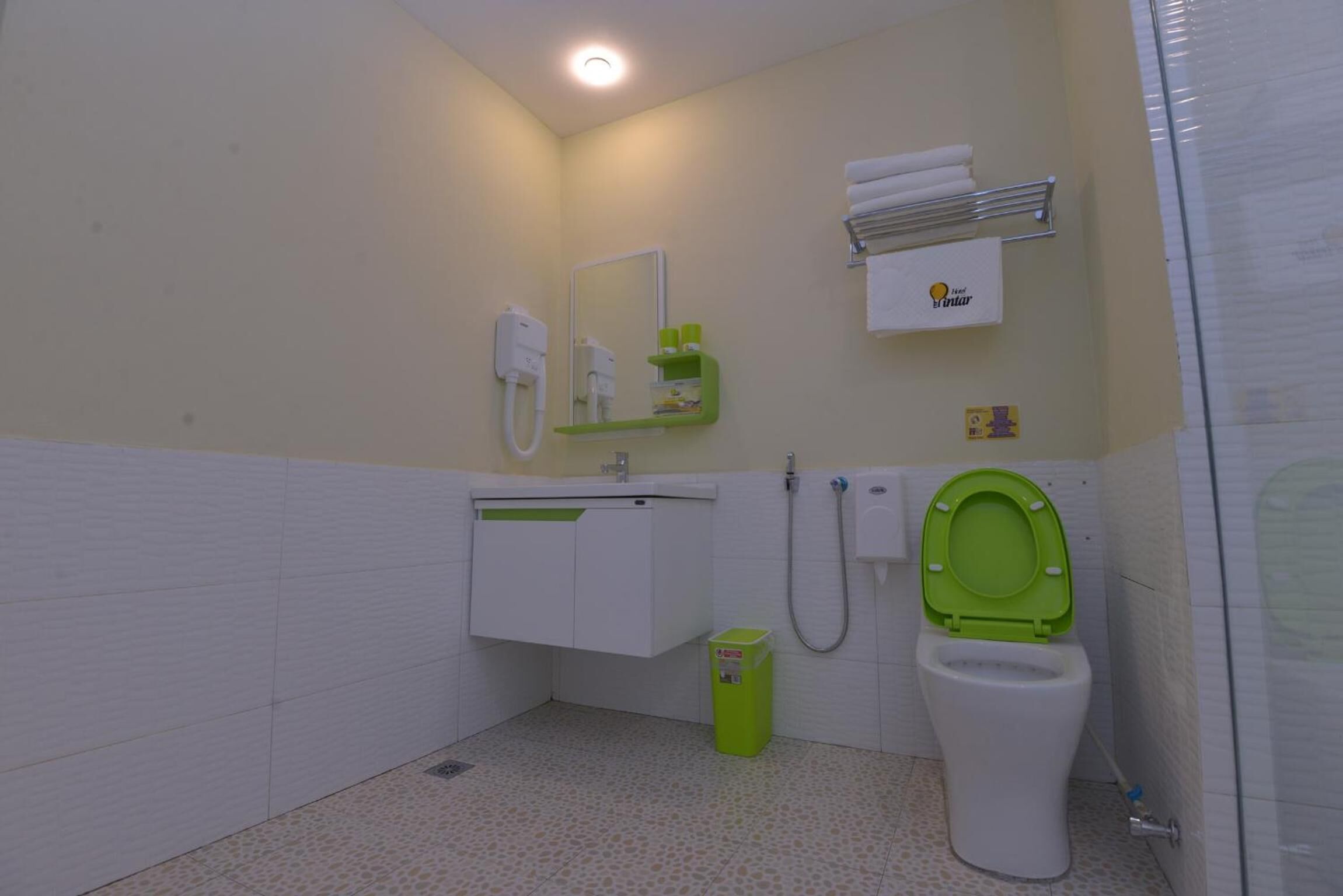 Un baño con inodoro, lavabo, espejo, toallero y un cubo de basura.
