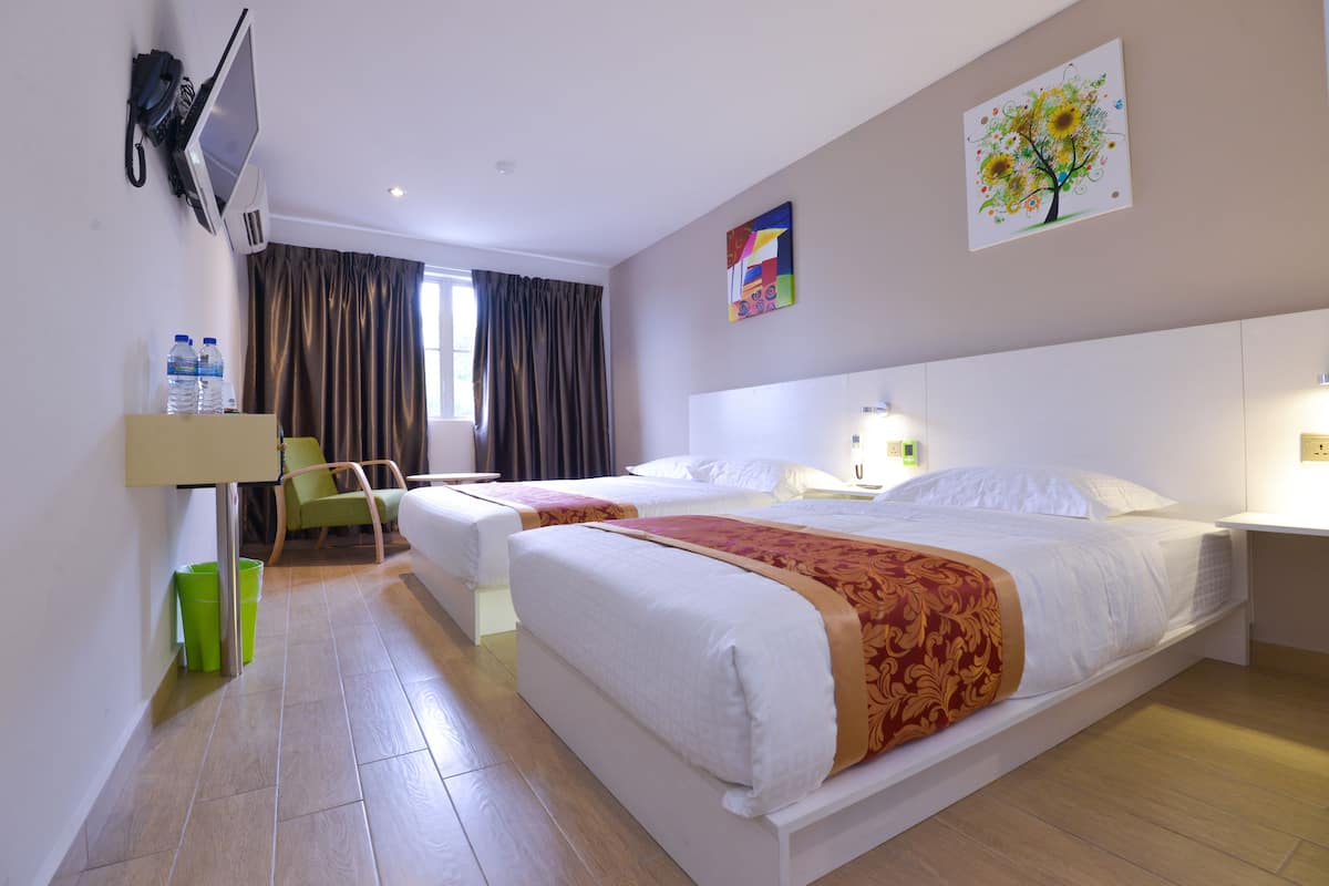 A hotel room with two beds, a TV, a desk, a chair, and a painting on the wall.