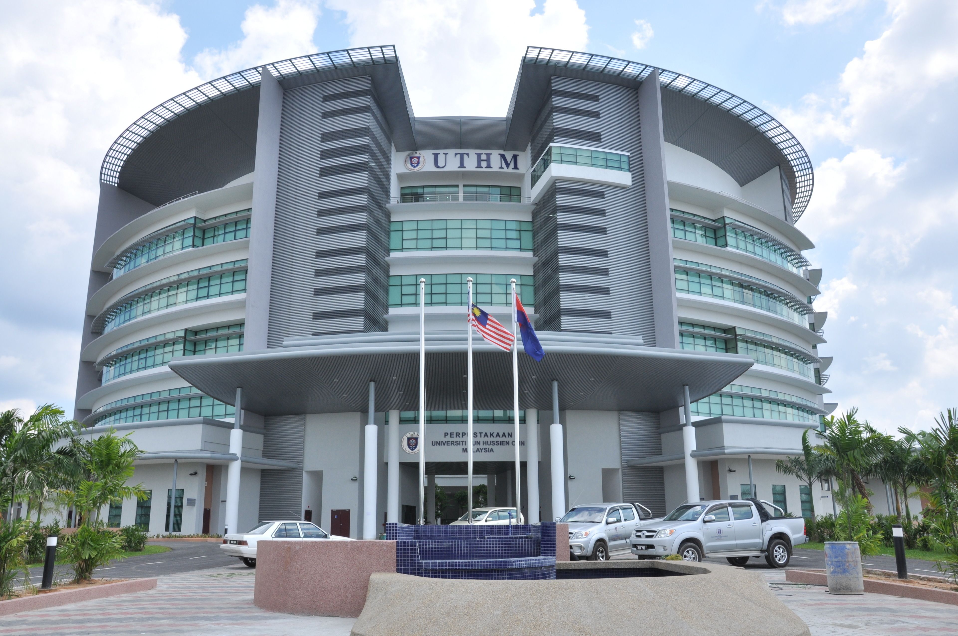 A modern building with the sign "UTHM" and "PERPSTAKAN UNIVERSITI HUSSEIN MALAYSIA" on the facade.