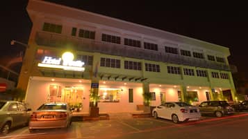 A hotel with a two-story structure, a reception area, and a parking lot with several cars.