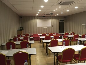 A conference room with tables and chairs, water bottles on each table, and a projector screen on the wall. - Hotel Pintar (Batu Pahat)