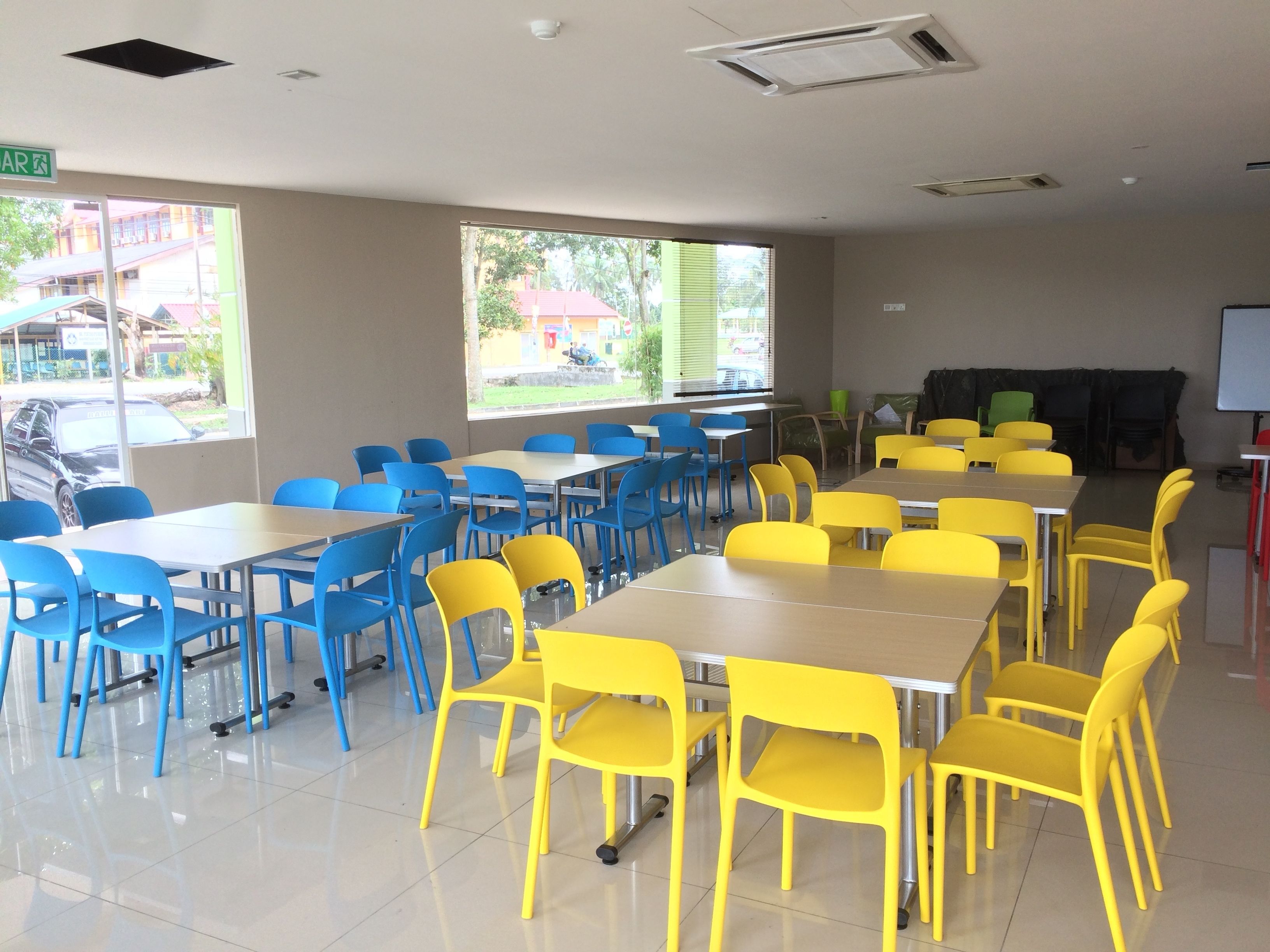 A classroom with blue and yellow chairs, tables, and a whiteboard.