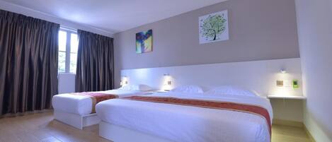 A hotel room with two beds, a large window with curtains, and artwork on the walls.