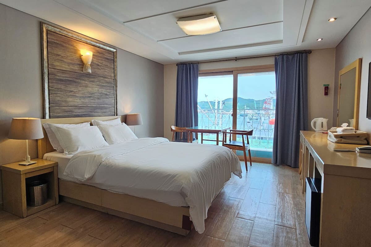 Una habitación de hotel con una cama grande, mesitas de noche, un escritorio con teléfono y televisor.