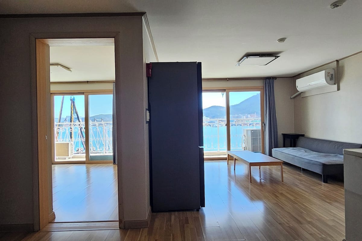 Amplia sala de estar con balcón, sofá y mesa de comedor.
