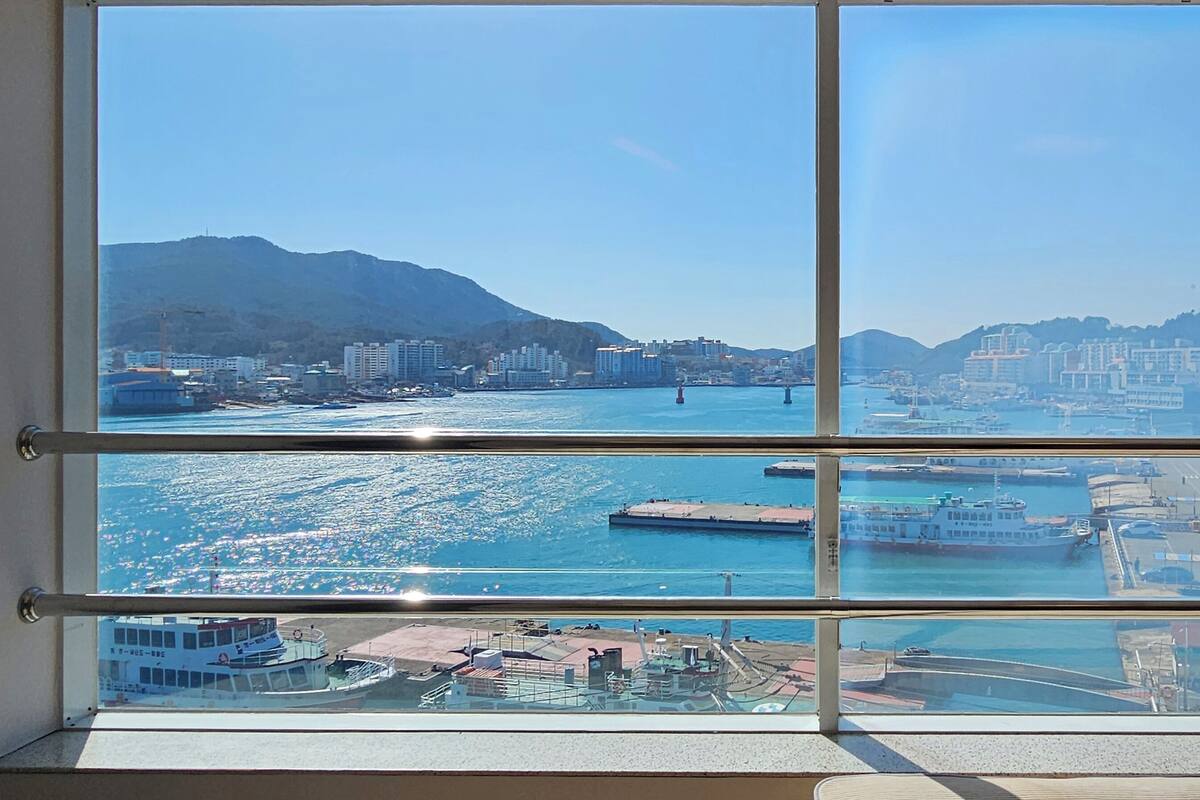 Vista de varios niveles de una ciudad costera a través de una ventana con marco de metal.