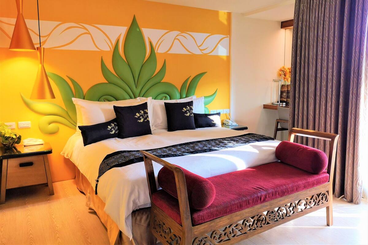 A hotel room with a bed, a nightstand, a lamp, and a chair.