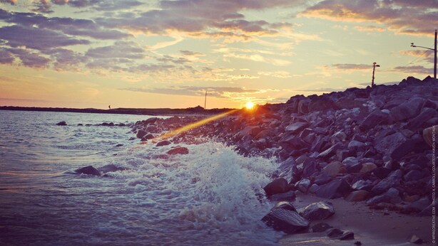 A rocky shoreline with waves crashing against the rocks during sunset. - Haven Montauk (Montauk)