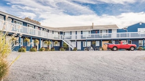 Un motel avec une allée en gravier, un pick-up rouge et un escalier menant à l’étage.
