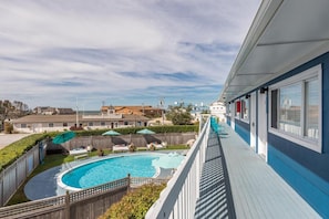 A poolside view with a wooden deck, a swimming pool, and a building with a blue exterior. - Haven Montauk (Montauk)