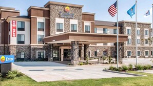 A Comfort Inn & Suites hotel with a stone facade, a covered entrance, and American flags. - Comfort Inn & Suites Woodward (Woodward)