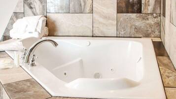 A rectangular bathtub with a single faucet, set against a tiled wall with a variety of stone patterns.